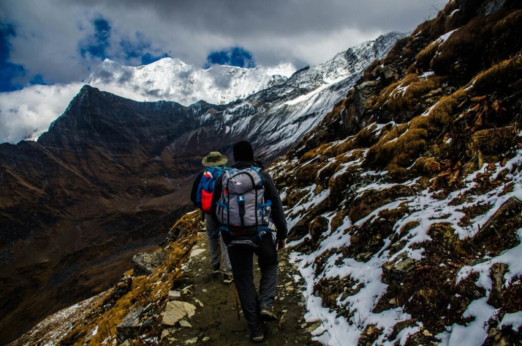 Dois jovens realizando trekking em uma montanha carregando suas mochilas